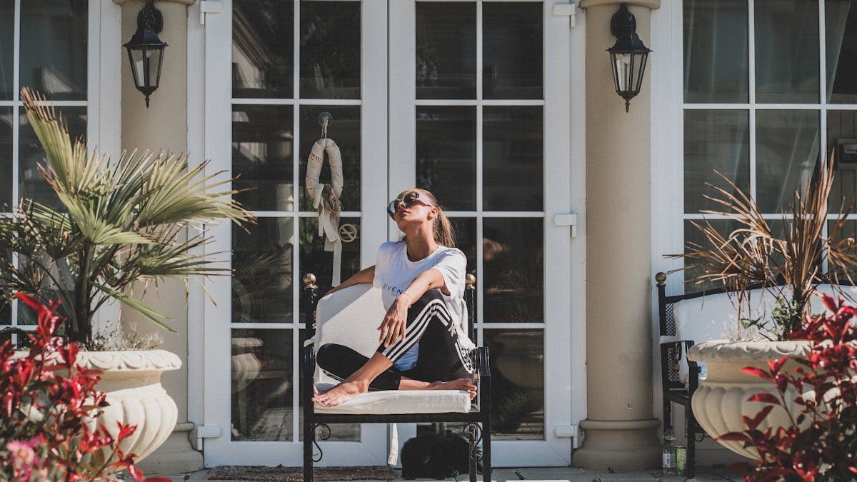 Woman enjoying a sunny day on a modern porch surrounded by stylish garden décor.
