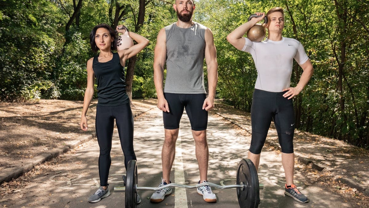 Three adults exercising outdoors with weights, promoting fitness and diversity.